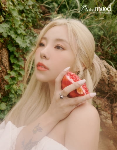 Wheein, holding a pomegranate in her hand